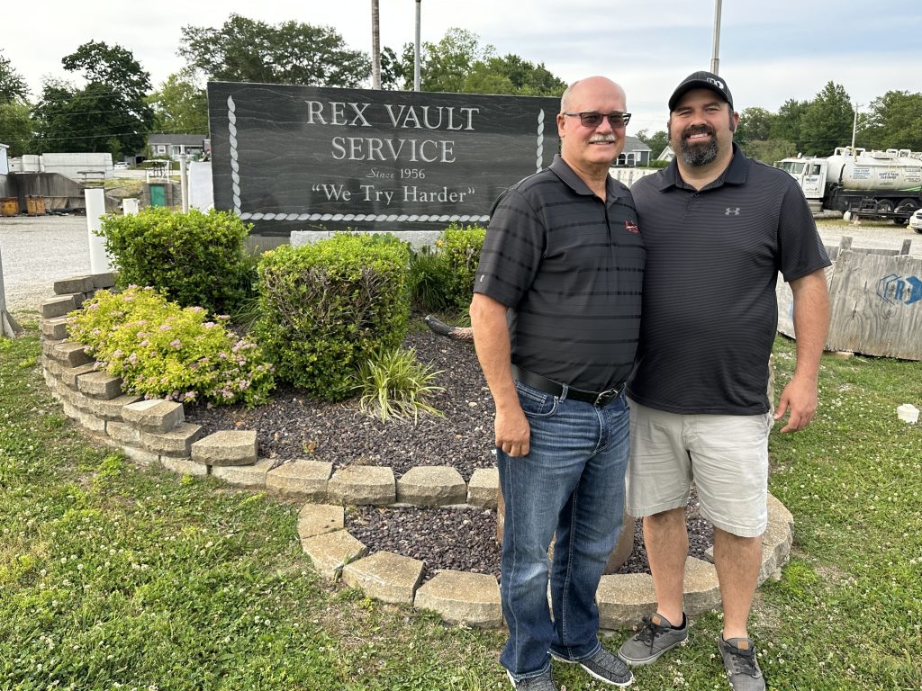 Mark and Lucas Bolander in front of the rex vault sign